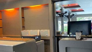 A reception area with a desk, computer, and a window with a view of the outdoors. - Hide Hostel (Koh Phangan)