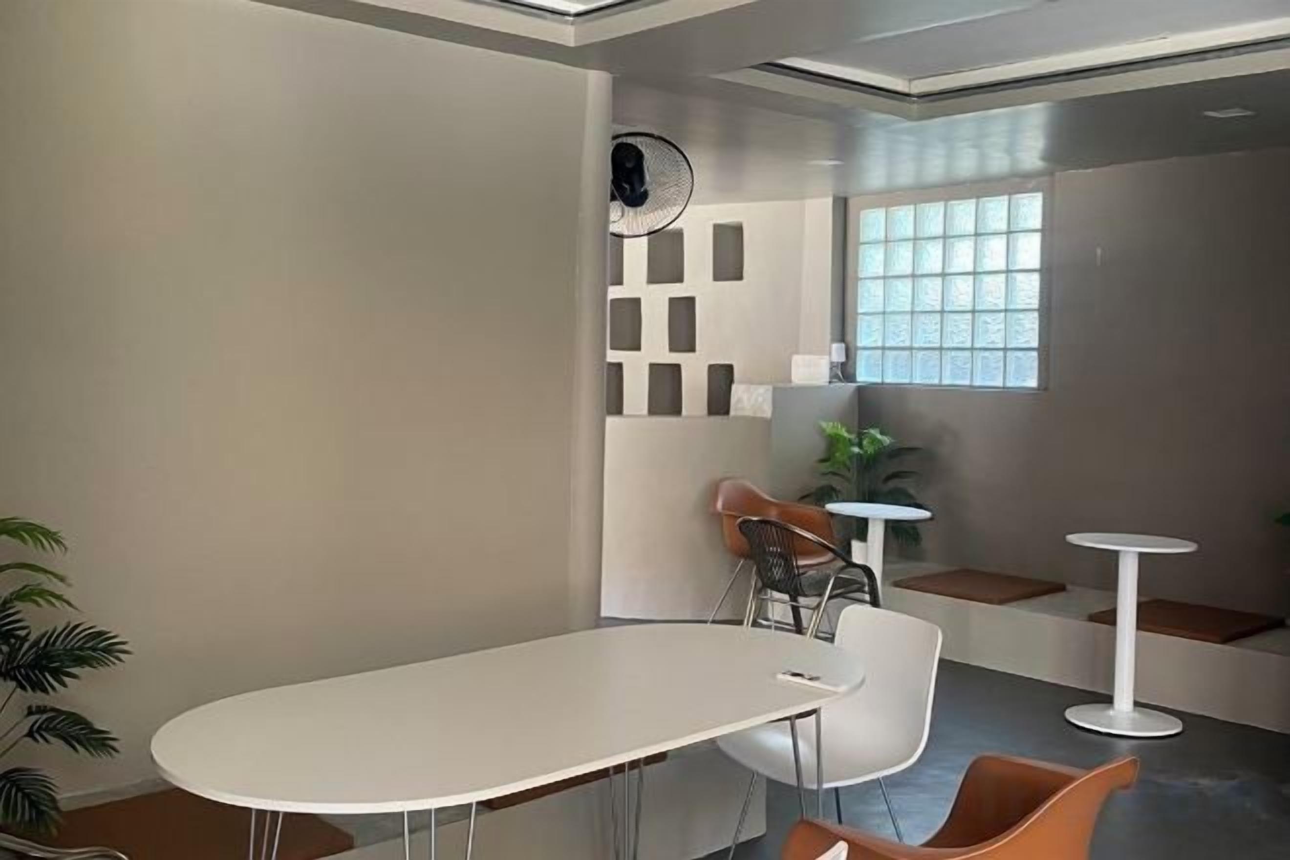 A modern office space with a white table and chairs, a small white table, and a window with a view.