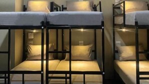 Bunk beds with headboards, a wall-mounted light, and a small shelf. - Hide Hostel (Koh Phangan)