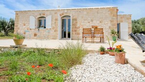A stone building with a patio, outdoor seating, and potted plants.