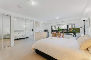 A modern bedroom with a large bed, a desk, and a TV.