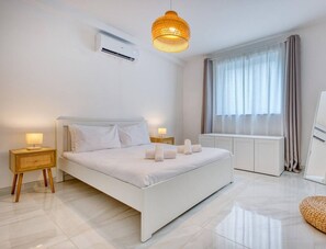 Un dormitorio moderno con una cama grande, lámparas de noche, una lámpara colgante, un ventanal con cortinas y un espejo.