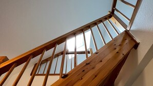 A wooden staircase with a glass balustrade leading to a door.