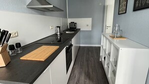 A compact kitchen with a black countertop, white cabinets, a built-in stove, and a microwave.