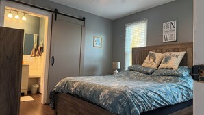 A bedroom with a bed, a ceiling fan, a nightstand, a lamp, a window with blinds, a wall clock, and a framed map. - Luxury Townhouse near Downtown and Beaches with Hot Tub (Mount Pleasant)
