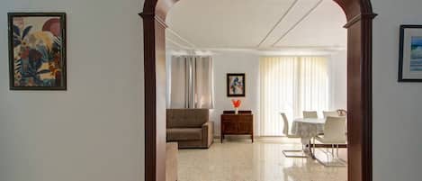 A hotel room with a living area, a dining table, and a sofa.