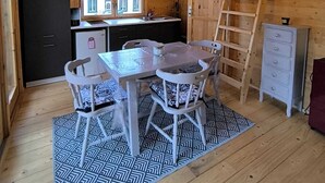 Interno di una baita in legno con zona pranzo, angolo cottura e camera soppalcata.