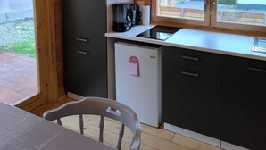 Una cucina compatta con pareti in legno, un frigorifero, un lavello e una finestra con vista su un giardino.