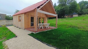 Una baita di legno con tetto rosso, un portico coperto e un vialetto sterrato che conduce all'ingresso.
