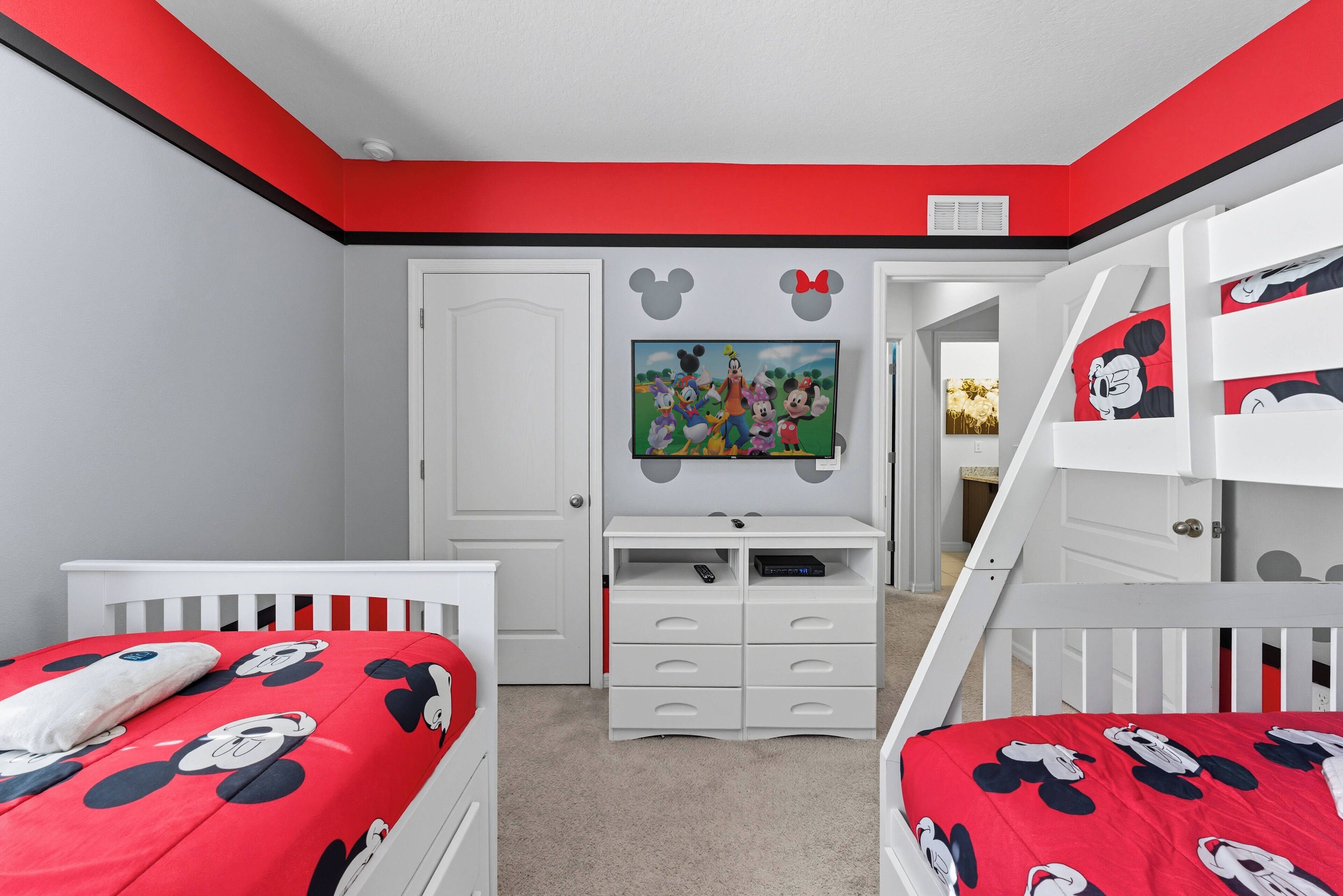 A child's bedroom with two beds, a TV, and a white dresser.