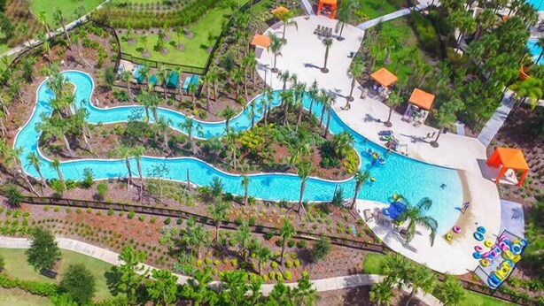 An aerial view of a resort with a winding pool, palm trees, and lounge areas. - 7049 Solterra 6 bedrs 18guests pool summer kitchen (Davenport)