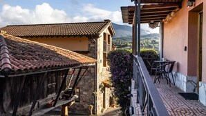 A traditional stone building with a tiled roof, a balcony with outdoor seating, and a view of mountains in the background. - The Village Retreat - Al Llagar (Sales)