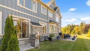 A two-story house with a covered patio, outdoor seating, and a grill. - Family Townhome at Blue with Resort Shuttle (The Blue Mountains)
