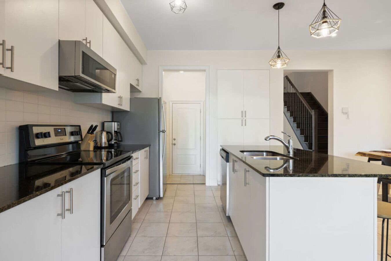 Una cocina moderna con una isla central, electrodomésticos de acero inoxidable e iluminación colgante.