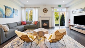 A modern living room with a fireplace, a large TV, and a sofa. - Family Townhome at Blue with Resort Shuttle (The Blue Mountains)