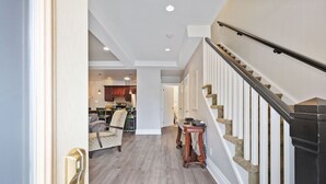 A spacious hallway with a wooden floor leading to a staircase with a black handrail and white balusters. - Collingwood Hideaway for 6 | 10 Mins to Blue Mtn (Collingwood)