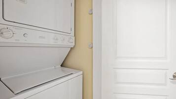 A white stacked washer and dryer unit with control knobs and a door.
