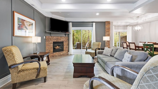 A spacious living room with a fireplace, comfortable seating, and a dining area visible through an open door. - Collingwood Hideaway for 6 | 10 Mins to Blue Mtn (Collingwood)