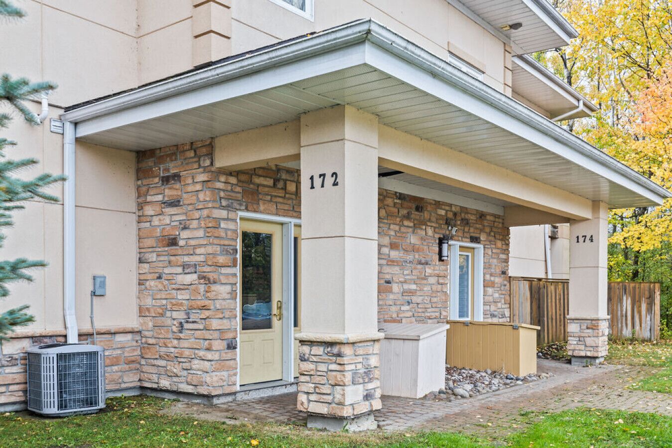A residential building with a stone facade, numbered 172 and 174, featuring a covered entryway and a small porch area.