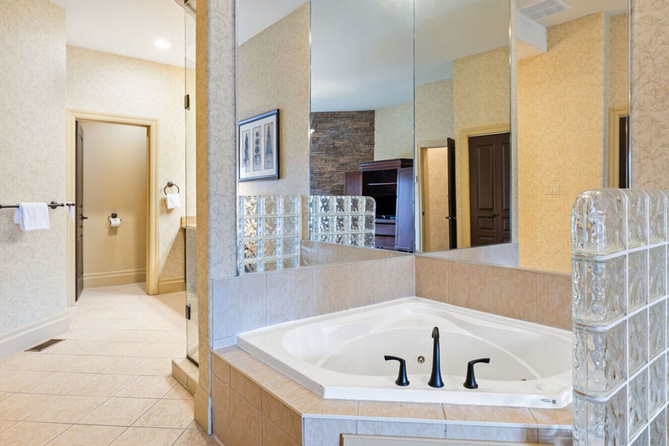 A modern bathroom with a large bathtub, a glass shower enclosure, and a mirror reflecting the room.