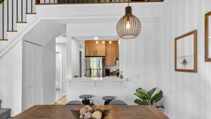 A modern kitchen with wooden cabinets, a stainless steel refrigerator, and a hanging pendant light.