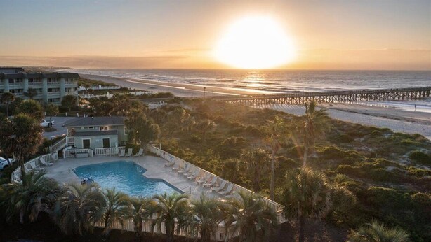 Een resort met een zwembad, strand en pier.