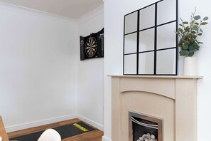 Ein Zimmer mit Kamin, Dartscheibe und Spiegel an der Wand.