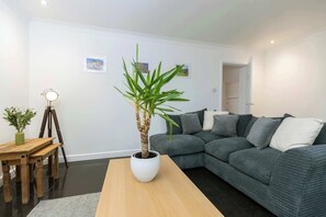 A modern living room with a grey sofa, a wooden coffee table, and a potted plant.
