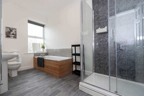 Un baño moderno con inodoro, lavamanos, bañera y cabina de ducha de vidrio.