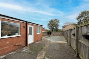 A narrow alleyway with a brick building on the left and a wooden fence on the right. - Central Bishop - 4 Beds, Games Room, Secure Parking (Bishop Auckland)