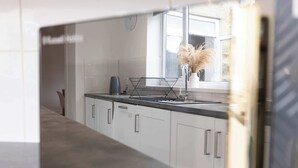 Een moderne keuken met witte kasten, een zwart aanrecht en een raam met uitzicht.