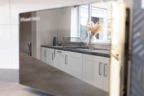 A modern kitchen with white cabinets, a black countertop, and a window with a view.
