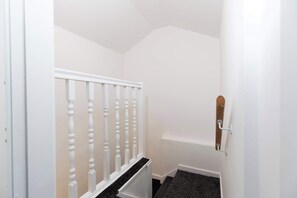 Eine schmale Treppe mit weißen Geländern und einem hölzernen Handlauf.