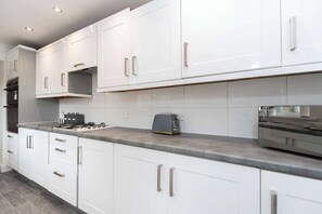 A modern kitchen with white cabinets, stainless steel appliances, and a grey countertop. - Central Bishop - 4 Beds, Games Room, Secure Parking (Bishop Auckland)