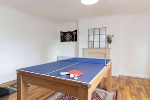 A ping pong table with a blue playing surface and a net, a red and white table tennis paddle, and a white ball. - Central Bishop - 4 Beds, Games Room, Secure Parking (Bishop Auckland)