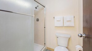 Un bagno con doccia vetrata, un WC e due asciugamani appesi al muro.