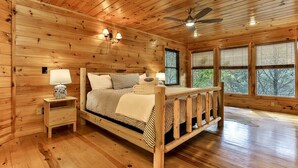 Ein Schlafzimmer einer Holzhütte mit einem Bett, Nachttischen und einem Deckenventilator.
