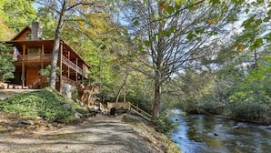 Eine Hütte mit Terrasse, Kiesweg und Fluss.