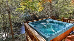 Ein Whirlpool, umgeben von einer Holzterrasse und einem Wald.