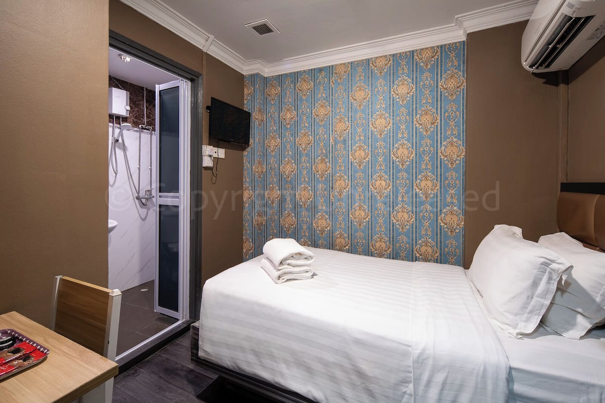 Une chambre d’hôtel équipée d’un lit, d’une douche et d’un téléviseur fixé au mur.