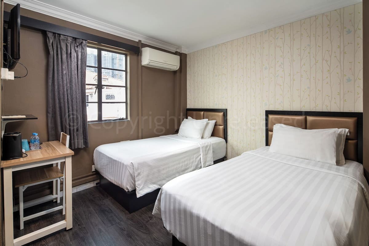 Une chambre d’hôtel avec deux lits, un bureau et un appareil de climatisation.