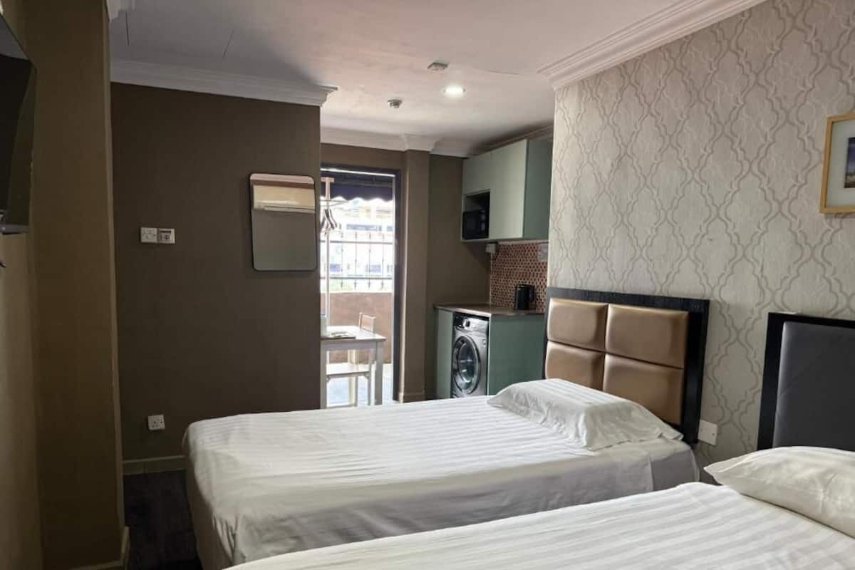 Une chambre d’hôtel avec deux lits, un lave-linge et une petite kitchenette.