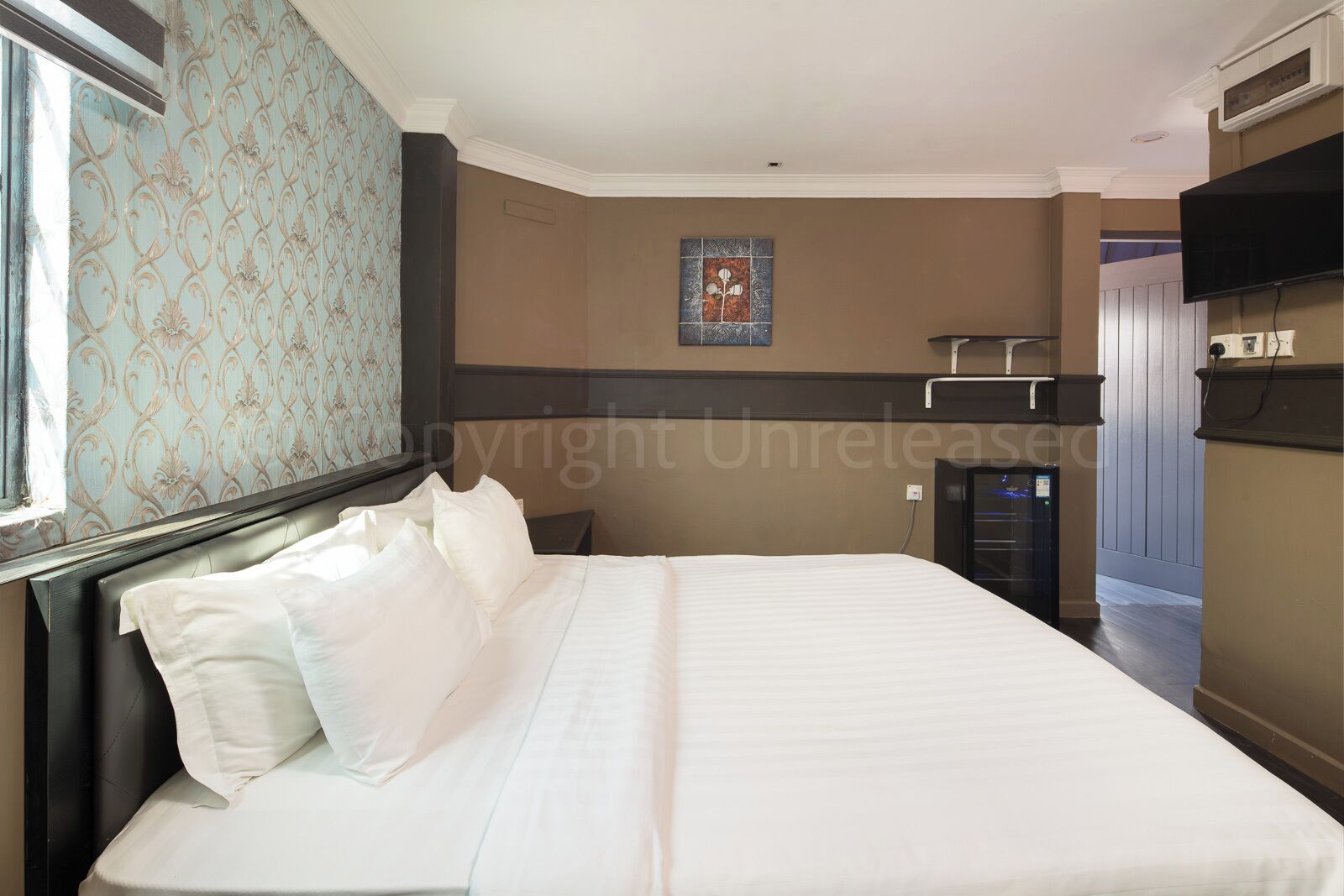 Quarto de hotel com cama grande, televisão de tela plana na parede e pequena mesa de trabalho com cadeira.