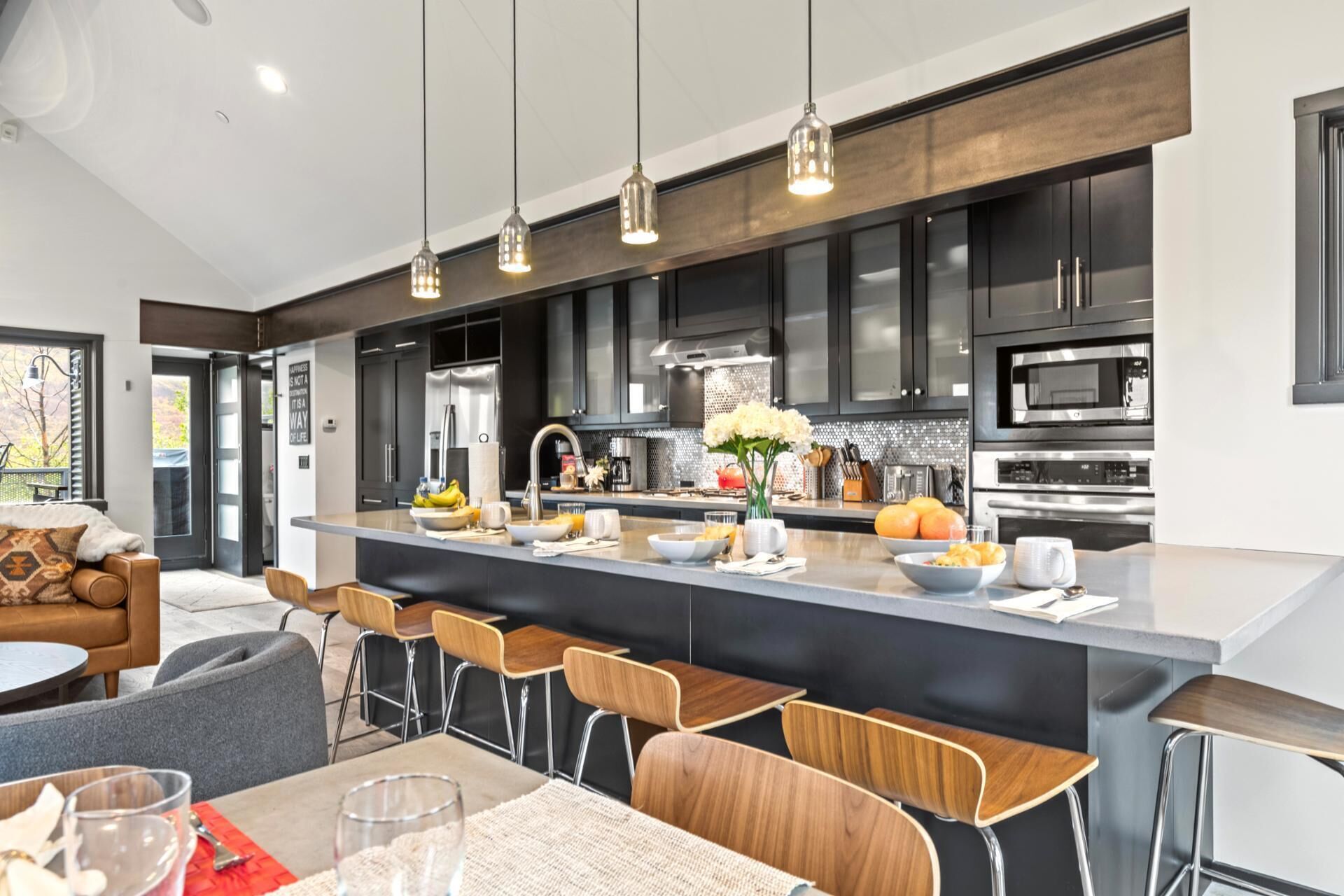 Uma cozinha moderna com uma ilha central, banquetas de bar e um espaço de refeições com mesa e cadeiras.
