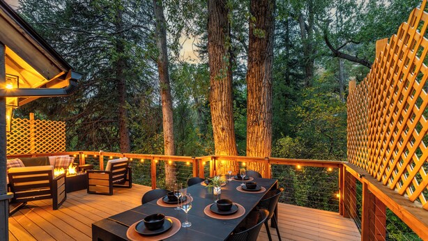 An outdoor deck with a dining table set for four, surrounded by chairs, and a fire feature. - Creek Front with Firepit Patio, BBQ & Theatre Near Hot Springs, Hiking, Biking (Glenwood Springs)