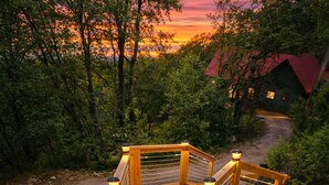 A wooden staircase leading to a house with a red roof, surrounded by trees and a sunset in the background. - Creek Front with Firepit Patio, BBQ & Theatre Near Hot Springs, Hiking, Biking (Glenwood Springs)