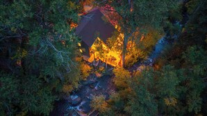 An aerial view of a cabin surrounded by dense forest, with a visible stream and a small bridge leading to the cabin. - Creek Front with Firepit Patio, BBQ & Theatre Near Hot Springs, Hiking, Biking (Glenwood Springs)