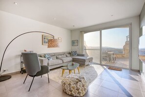Ein modernes Wohnzimmer mit einem grauen Sofa, einem runden Couchtisch und einer Stehlampe.