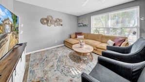 A living room with a sectional sofa, a coffee table, and a flat-screen TV. - Close to beaches, BBQ, workout gear, private yard (Largo)