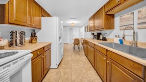 A kitchen with wooden cabinets, a white refrigerator, a sink, and a stove. - Close to beaches, BBQ, workout gear, private yard (Largo)